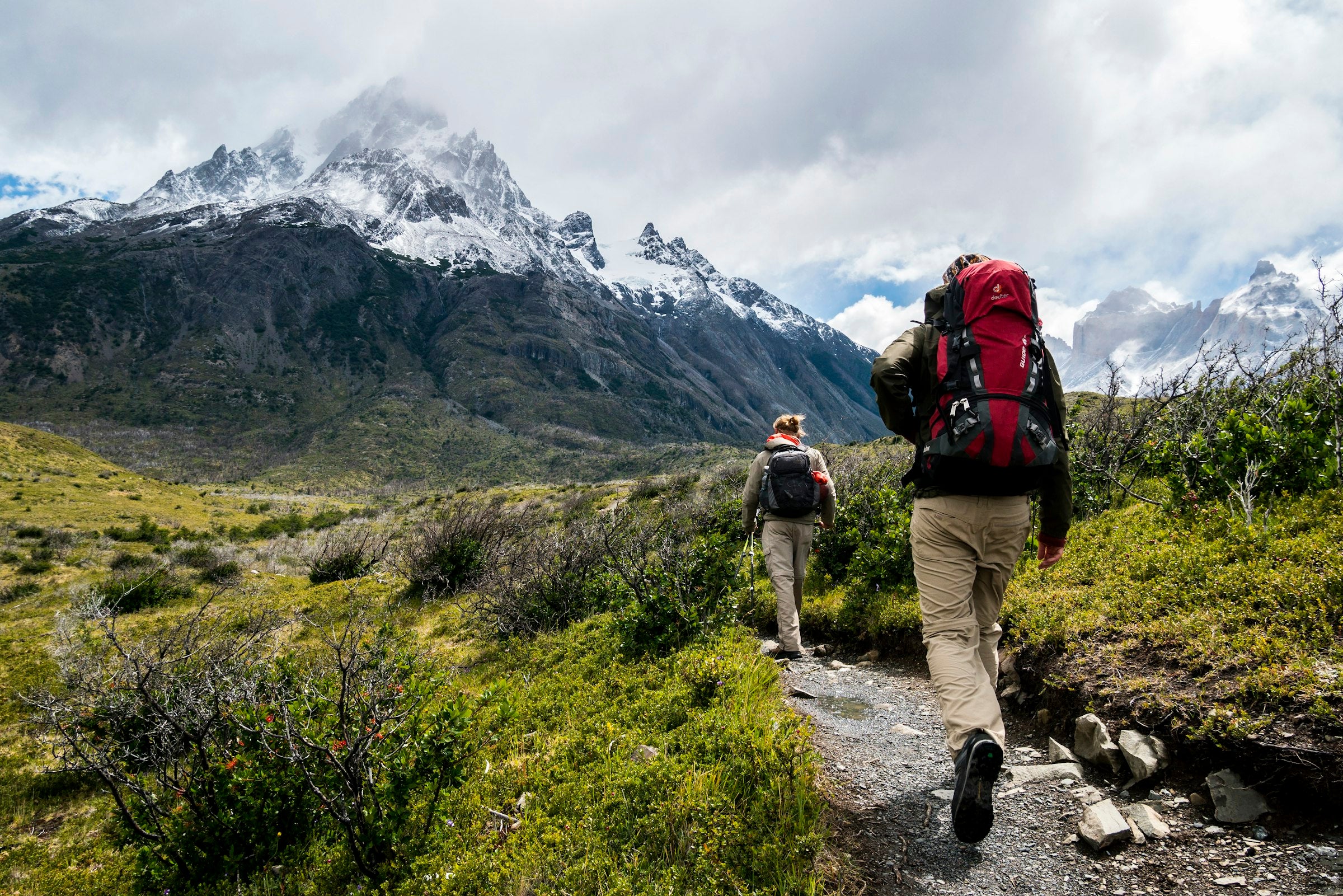 Hikers on mountain trail with snow-capped peaks - Auraeon outdoor adventure